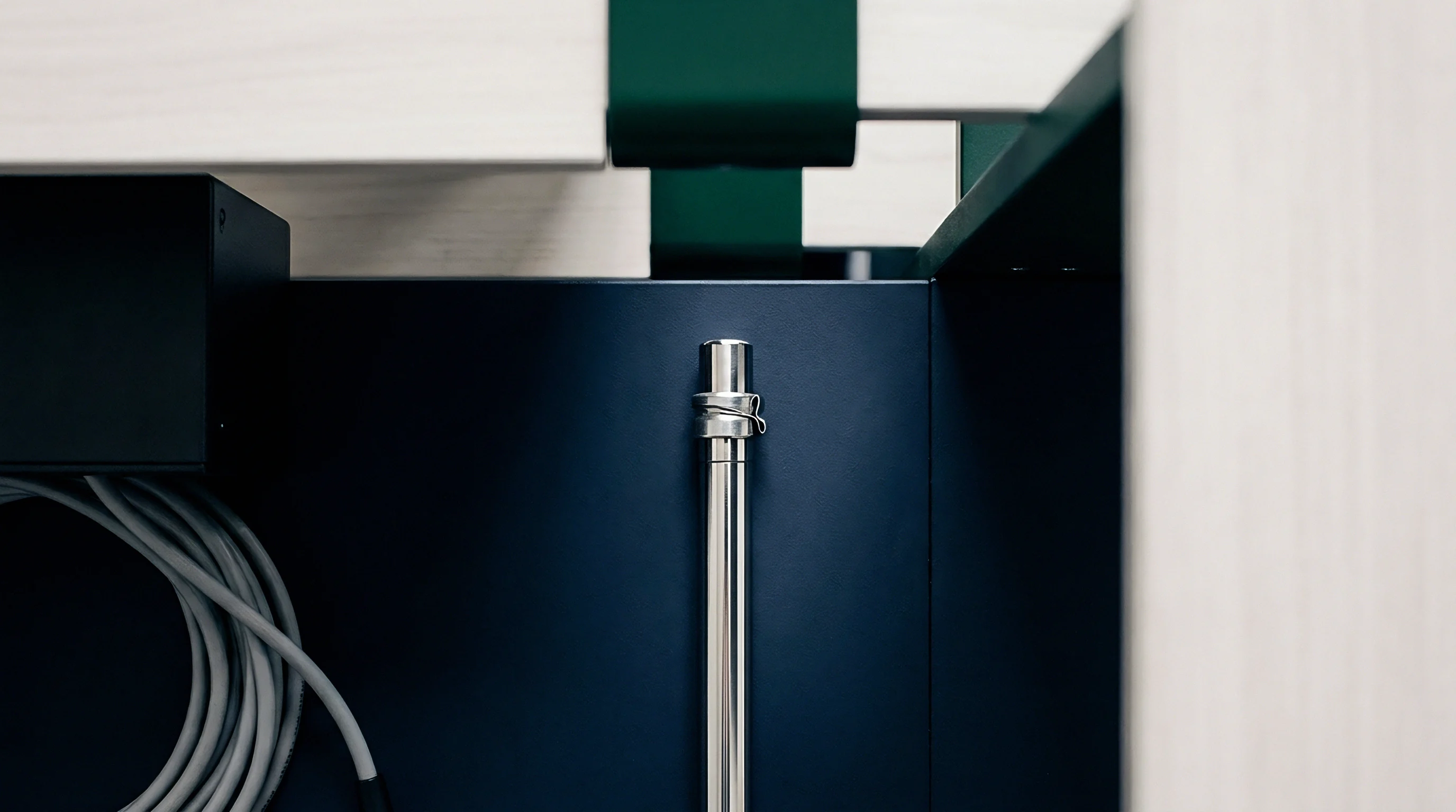 Steel retaining pin secures a vertical shaft against a dark blue metal panel inside a modular furniture assembly unit.
